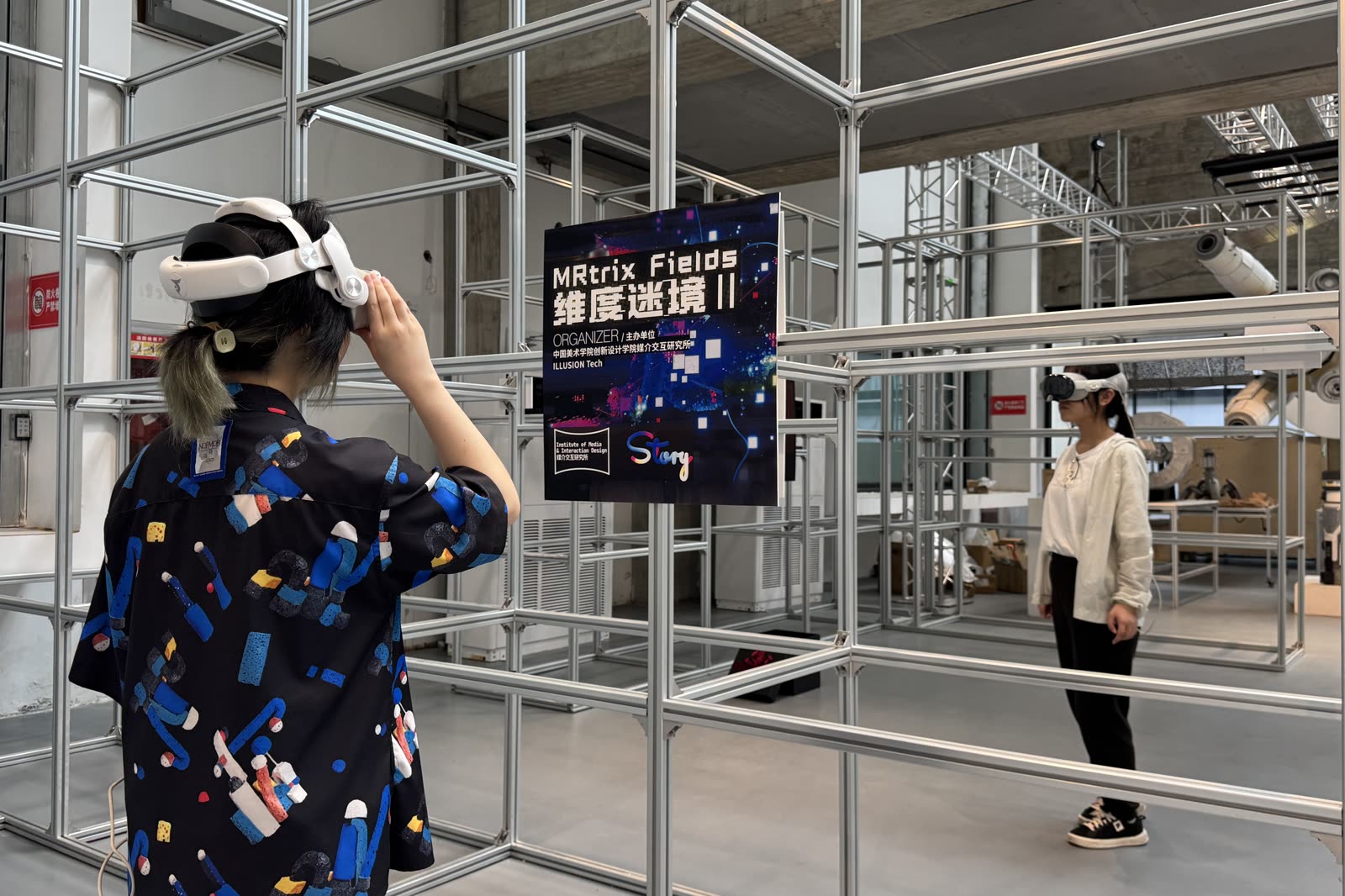 Two students in headsets at the MRtrix Fields II exhibition, inside an aluminium-frame gallery build