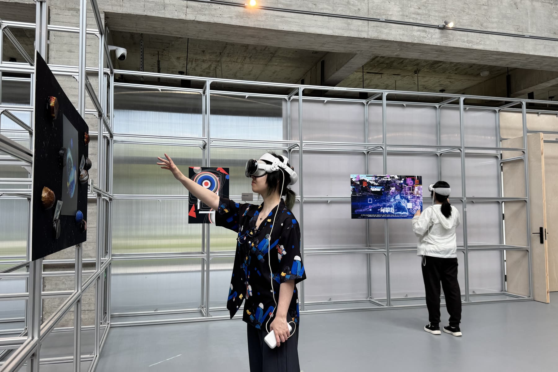 A visitor in a headset reaching towards a spatial work anchored to the gallery wall