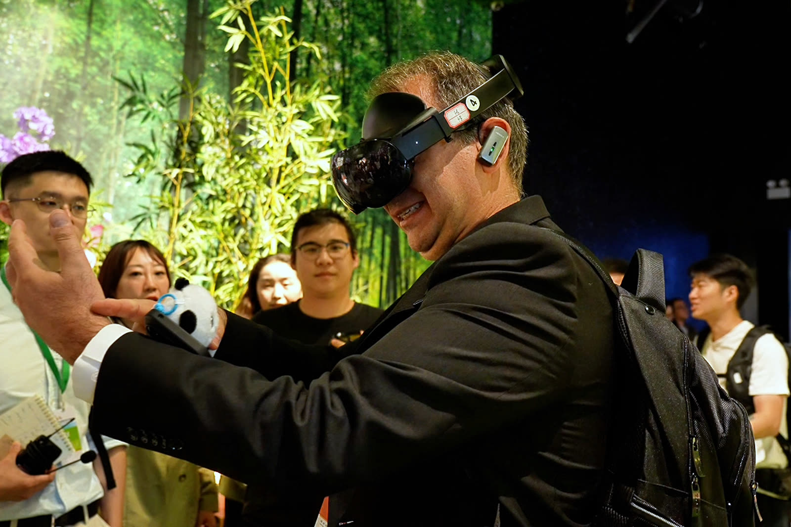 A visitor in a headset reaching into the physical bamboo set at the Chengdu Panda Base